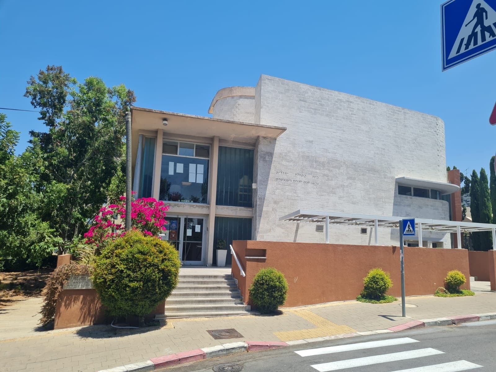 The Kehillat Yedidya building in Baka, pale stone with bougainvillea by the entrance steps