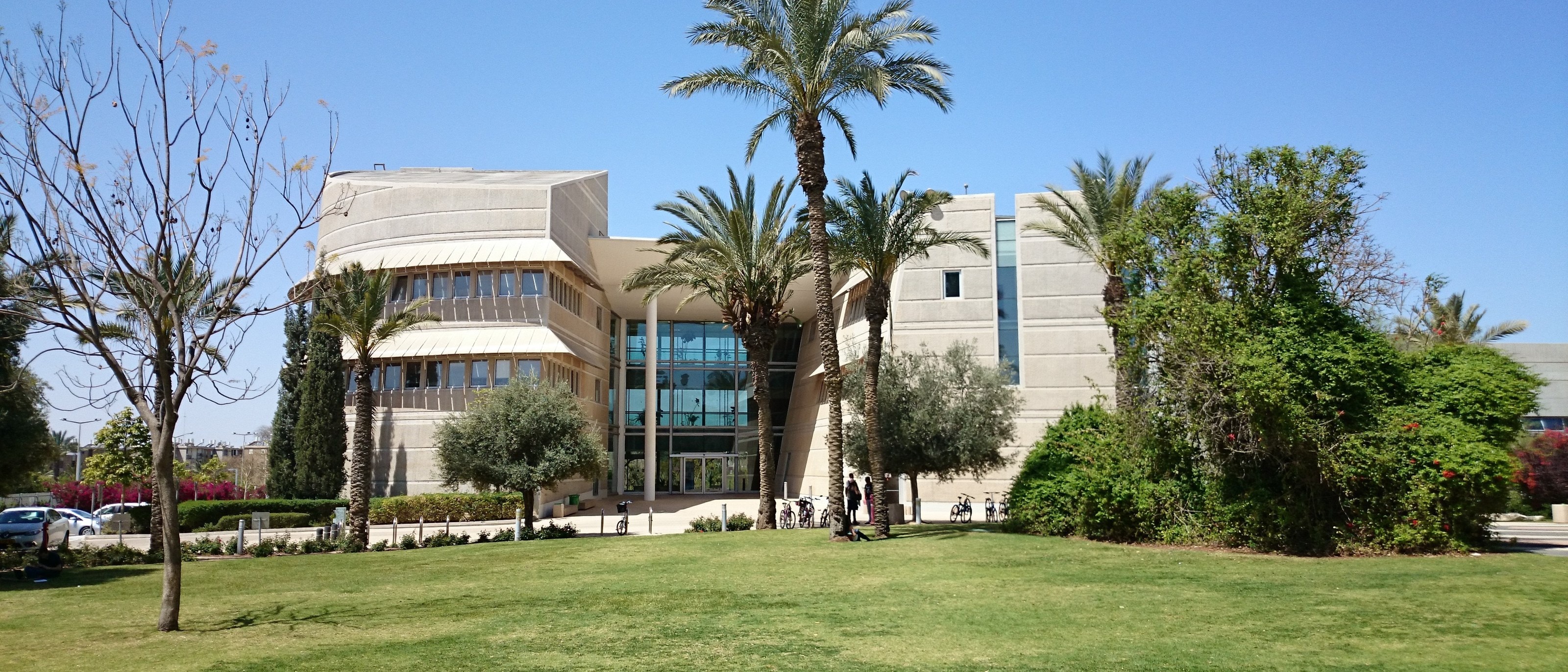 Ben-Gurion University of the Negev: a pale stone faculty building behind date palms and a wide lawn under a clear sky