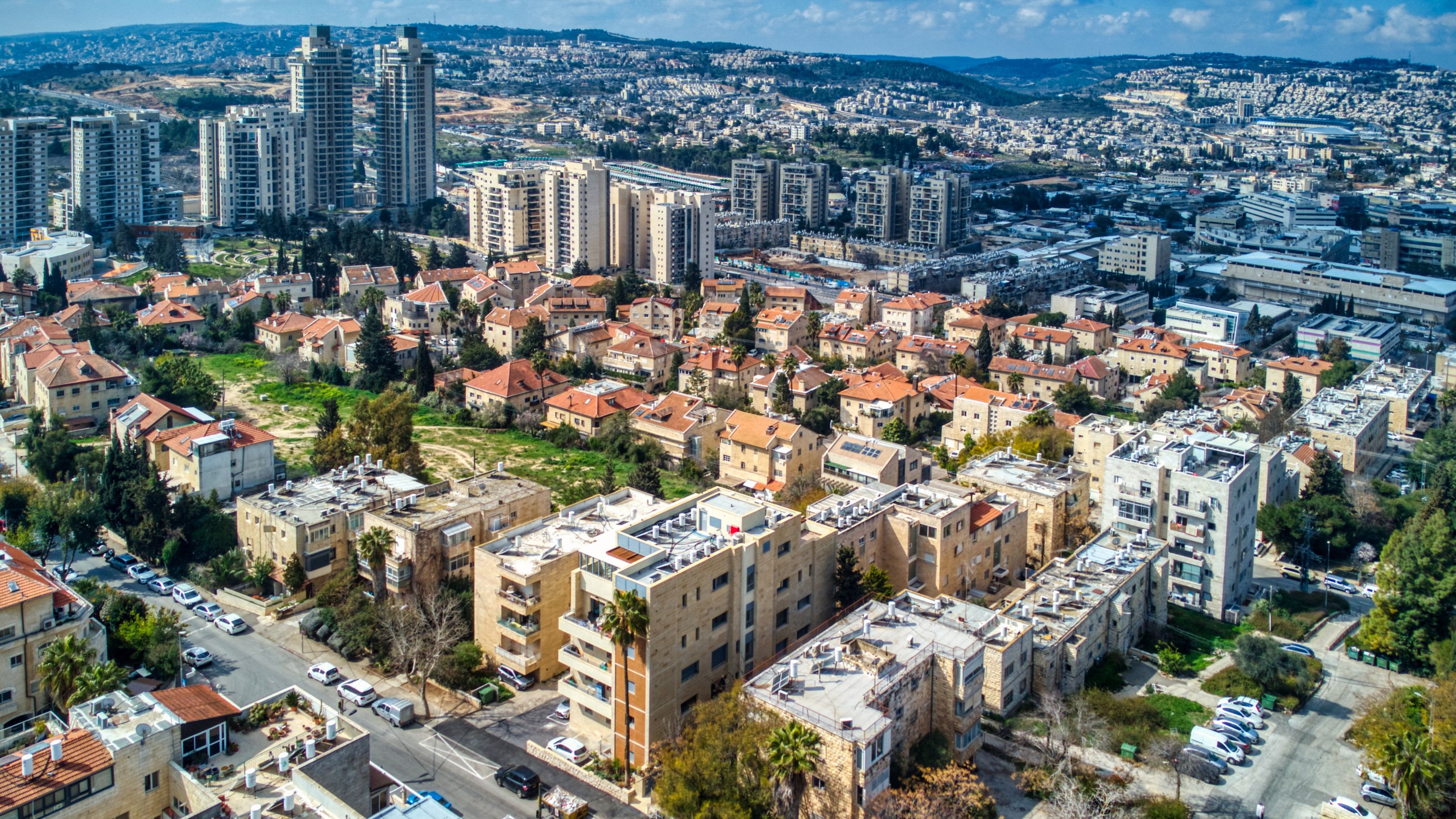Talpiot and Arnona from the air: stone apartment blocks and red-roofed houses, with Talpiot's towers behind